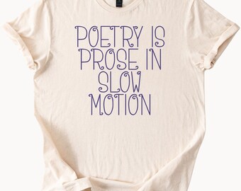 Op de afbeelding: Crèmekleurig T-shirt met de paarse tekst "POETRY IS PROSE IN SLOW MOTION". Het shirt heeft korte mouwen en een ronde hals. De stof ziet er zacht en comfortabel uit.