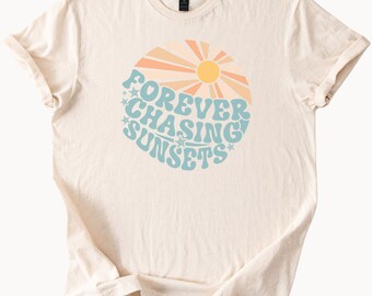 May include: A beige t-shirt with a graphic design of a sun with rays and the text "FOREVER CHASING SUNSETS" in blue and orange.