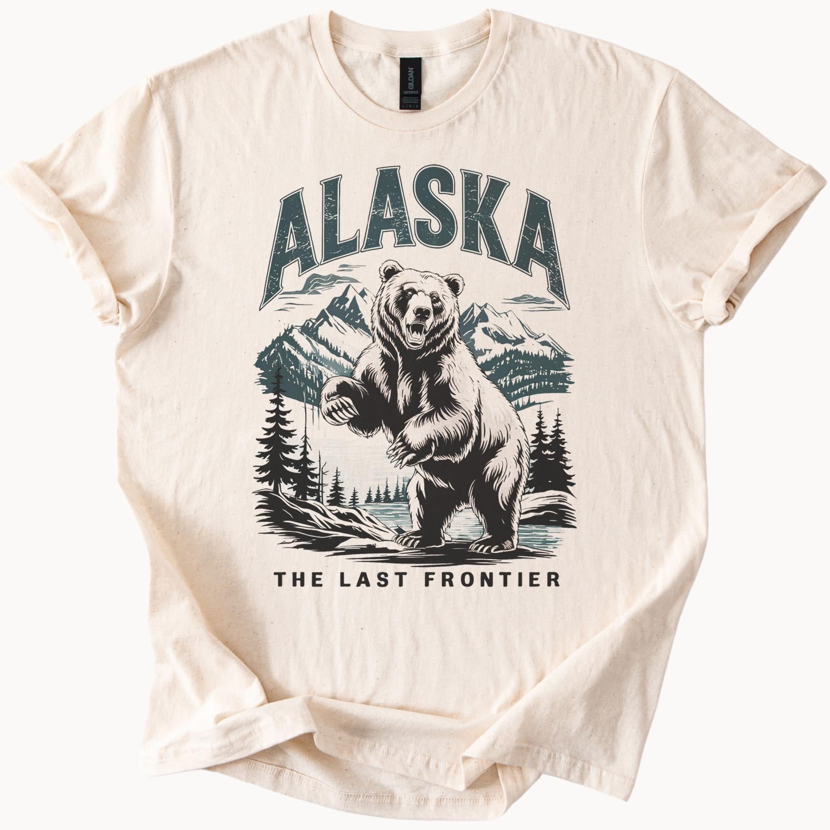 アラスカのグラフィックTシャツ。吠えるクマと山の風景が描かれてい 