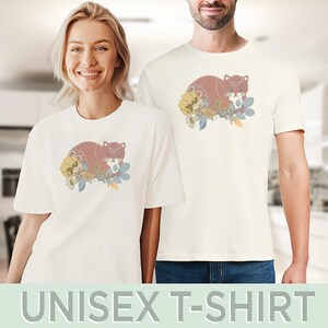 May include: Off-white unisex t-shirts with a cartoon fox design. The fox is brown with a white face, surrounded by yellow, blue, and green flowers. The text "UNISEX T-SHIRT" is at the bottom of the image.