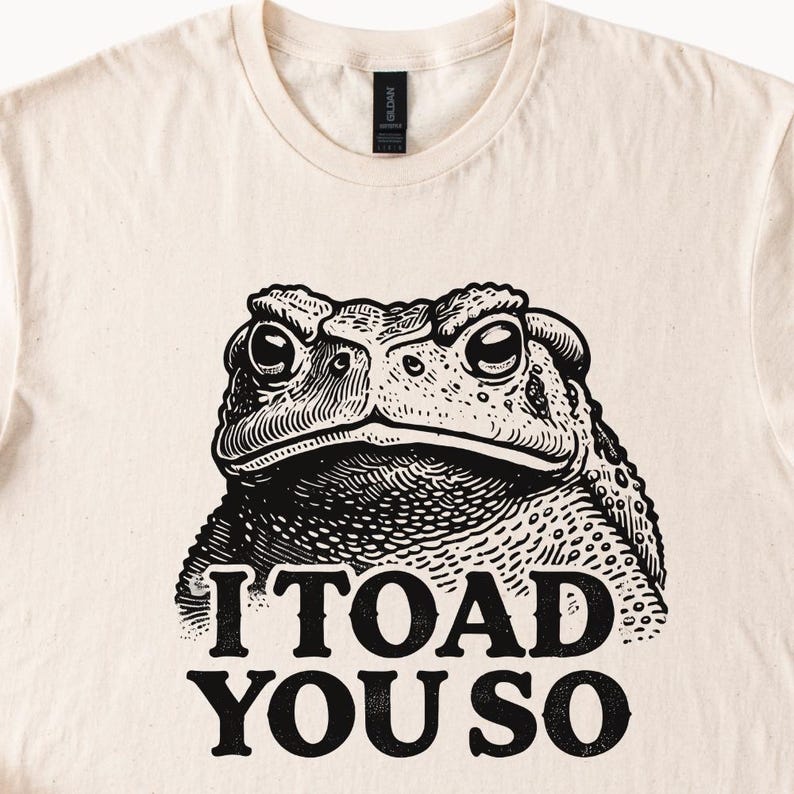 May include: A beige t-shirt with a black and white illustration of a toad and the text "I TOAD YOU SO".