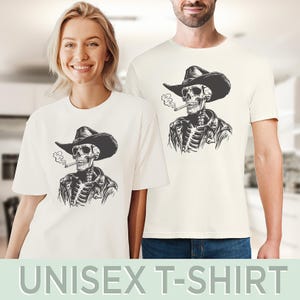 May include: Off-white unisex t-shirts with a black and white illustration of a skeleton in a cowboy hat and leather jacket, smoking a cigarette. The text "UNISEX T-SHIRT" is displayed at the bottom of the image.