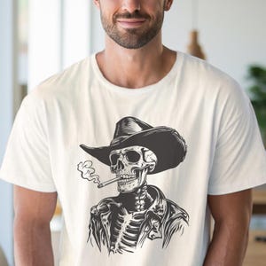 May include: White t-shirt with a black and white illustration of a skeleton in a cowboy hat and leather jacket, smoking a cigarette. The design is detailed, showing the rib cage and skull in a stylized manner.