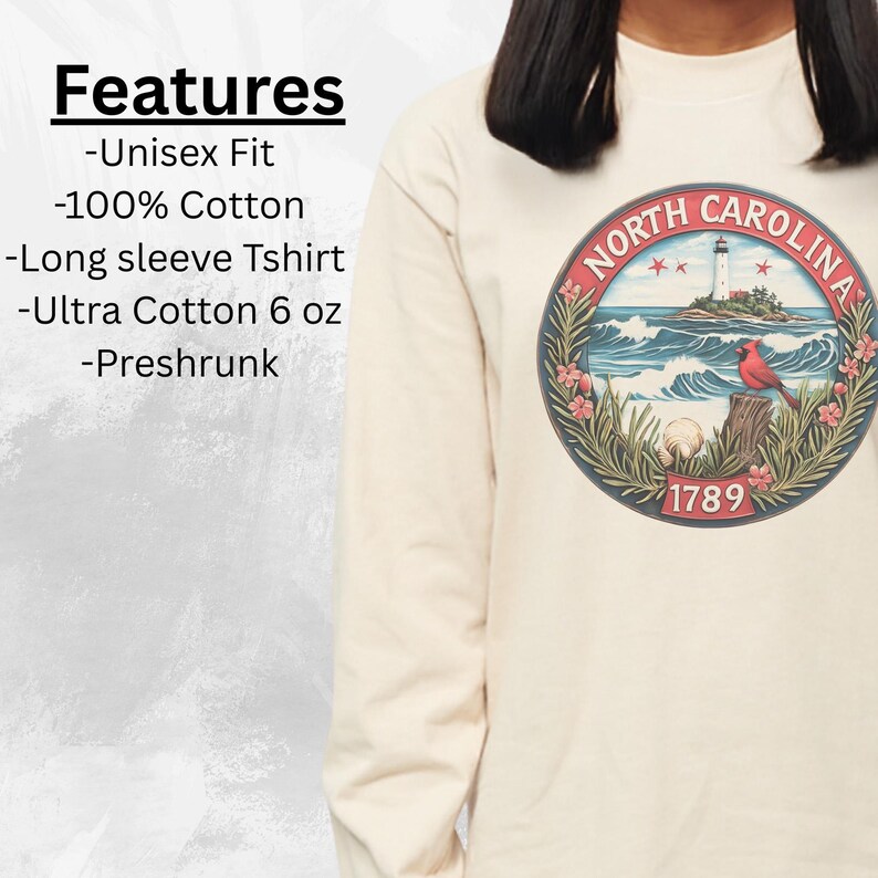 May include: Cream-colored long-sleeve t-shirt featuring a circular graphic of the North Carolina state seal. The seal depicts a lighthouse, ocean waves, and a cardinal. The shirt is made of 100% cotton and is preshrunk.