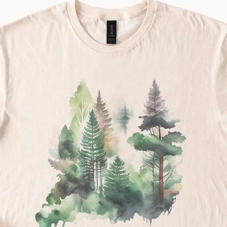 May include: A beige t-shirt with a watercolor design of a forest scene. The design features green, brown, and gray trees with a white background.