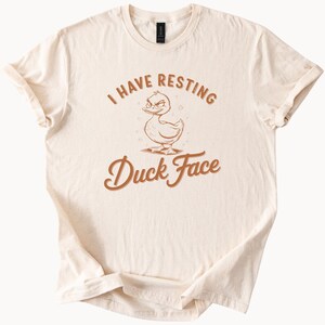 面白いアヒルの顔のTシャツ。かわいい漫画のアヒルのユーモアのある言葉が書かれた、動物愛好家へのギフト。