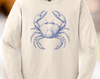 May include: Cream-colored long-sleeve shirt featuring a detailed blue crab illustration. The crab is centered on the shirt, with its claws raised. The design has a vintage, nautical feel, suitable for casual wear.