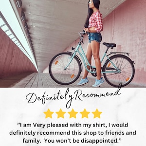 May include: Five star review with the text "I am Very pleased with my shirt, I would definitely recommend this shop to friends and family. You won't be disappointed."  A woman in a red and white plaid shirt and denim shorts stands next to a light blue bicycle.