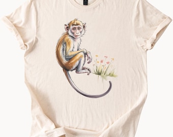 Joli bébé singe assis par fleurs sauvages, Nature graphique, art animalier, t-shirt en coton unisexe ivoire, dessin de la faune de la jungle