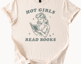 Op de afbeelding: Crèmekleurig T-shirt met de tekst "HOT GIRLS READ BOOKS" boven en onder een vintage illustratie van een lezende vrouw. De illustratie is in grijstinten en toont een vrouw met golvend haar en een overhemd.