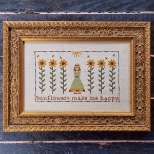 May include: A framed cross-stitch embroidery with a girl standing in a field of sunflowers. The embroidery reads "Sunflowers make me happy."