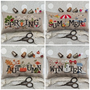 May include: Four embroidered pillow covers with the words "Spring", "Summer", "Autumn", and "Winter" stitched on them. Each pillow cover features a different seasonal theme with embroidered images of flowers, a beach scene, fall leaves, and a snowman.