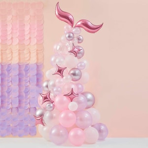 Può includere: Un arco di palloncini rosa e viola con un palloncino a forma di coda di sirena rosa in cima. L'arco è composto da palloncini di diverse dimensioni e forme, tra cui stelle e cuori.