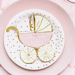Puede incluir: Platos de fiesta de bebé rosa y dorado con un diseño de cochecito blanco. Los platos están decorados con lunares blancos y purpurina dorada.