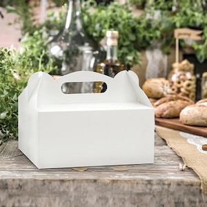 Könnte beinhalten: Eine weiße, rechteckige Backbox mit einem Griffausschnitt oben. Die Box steht auf einer rustikalen Holzoberfläche, mit Grün und Lebensmitteln im Hintergrund. Ideal für Kuchen und Gebäck.