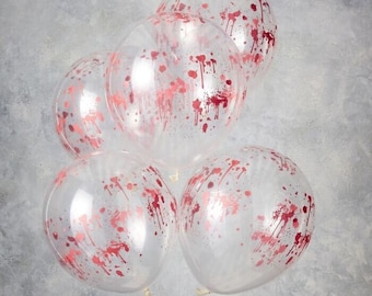 May include: Five clear balloons with a red splatter design. The balloons are round and appear to be filled with air. The red splatter design is evenly distributed across the surface of each balloon, creating a festive look.