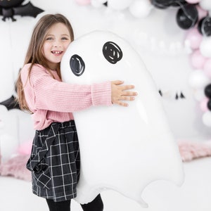 May include: A large, white, ghost-shaped foil balloon featuring two black circular eyes. The balloon has a smooth, glossy finish and is designed with a simple, rounded silhouette, capturing the classic appearance of a spectral figure for decor.