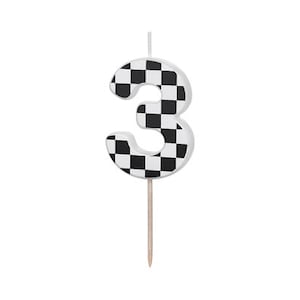 May include: Black and white checkered number three birthday candle. The candle is on a wooden stick.