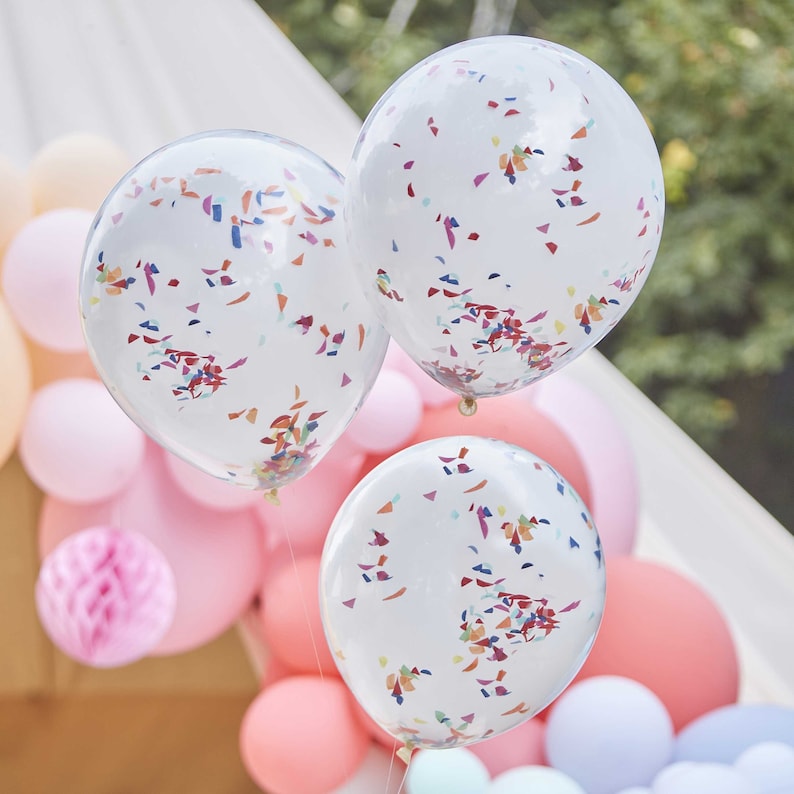 May include: Three white balloons with confetti inside. The balloons are decorated with colorful confetti and are tied together with a string.