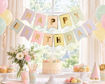 May include: A pastel-colored Happy Birthday banner with gold foil lettering, a frosted cake with sprinkles, cupcakes, a bouquet of flowers, paper cups, napkins, and balloons. The banner features pennant-shaped flags in shades of pink, yellow, and blue.