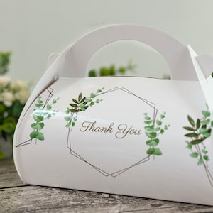 May include: White favour box with a handle, featuring a geometric design with green foliage and the text "Thank You".