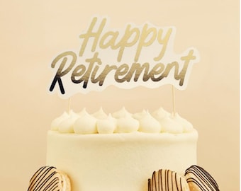 May include: A white frosted cake with a gold "Happy Retirement" cake topper. The cake is decorated with white frosting swirls and sits on a white plate. Three decorated cookies are placed around the cake.