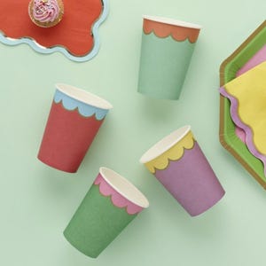 May include: Set of five colorful paper cups with scalloped edges. The cups are red, green, purple, and light green. Each cup has a different colored scalloped edge.