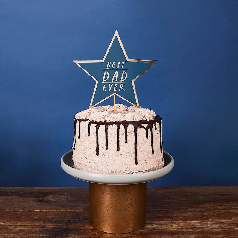 May include: A cake decorated with chocolate frosting and a blue star-shaped cake topper that says "Best Dad Ever".