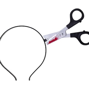 May include: A black headband featuring a prop pair of silver-toned scissors attached to the side. The scissor blades are decorated with a red splatter pattern resembling blood, while the handles are made of solid black plastic material.