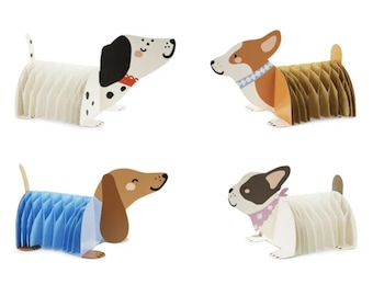 May include: Four paper dog decorations in various breeds. One is white with black spots, another is brown and white, a third is brown and blue, and the last is white with black and pink accents. Each dog has a honeycomb body.