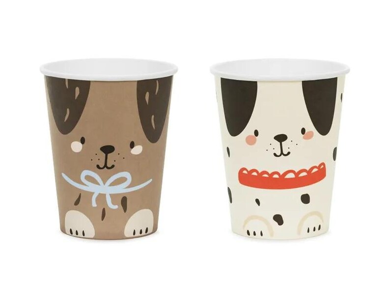 Puede incluir: Dos vasos de papel con ilustraciones de perros. Un vaso presenta un perro marr&oacute;n con una pajarita azul y el otro vaso presenta un d&aacute;lmata blanco y negro con un collar rojo.