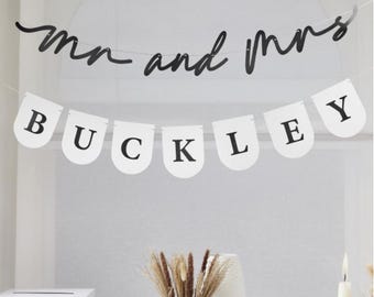 May include: White banner with black lettering that reads "Mr. and Mrs. Buckley". The banner is strung up on a wall.