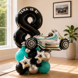 May include: A balloon arrangement featuring a large black number eight balloon with the text TARA IS 8! printed in white. Attached is a silver and teal race car foil balloon, accented with smaller black, silver, and teal round and star balloons.