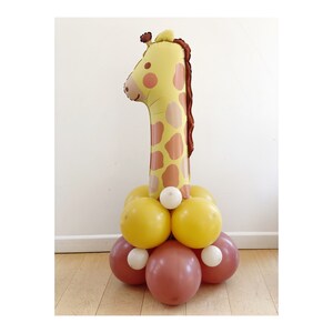 May include: A yellow and brown giraffe balloon number one with a white, yellow, and brown balloon base.