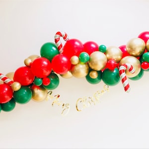 May include: A Christmas balloon garland in red, green, and gold, with candy cane accents. The words "Merry Christmas" are displayed in gold script, creating a festive holiday atmosphere. Ideal for seasonal decorations.