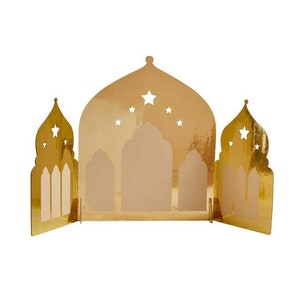 K&ouml;nnte beinhalten: Eine goldfarbene dekorative Papierlaterne in Form einer Moschee. Die Laterne hat ausgeschnittene Sternformen und bogenf&ouml;rmige Fenster. Die Laterne ist so konzipiert, dass sie aufrecht steht und wahrscheinlich f&uuml;r festliche Anl&auml;sse verwendet wird.