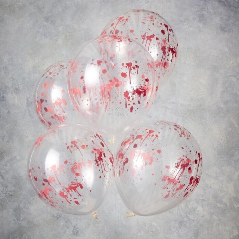 May include: Five clear balloons with a red splatter design. The balloons are round and appear to be filled with air. The red splatter design is evenly distributed across the surface of each balloon, creating a festive look.