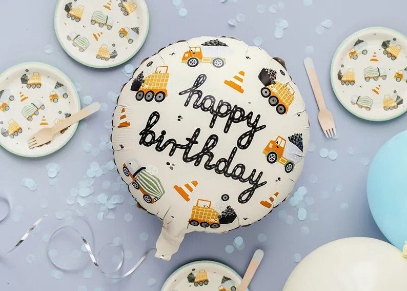 Pode incluir: Um bal&atilde;o branco com tema de constru&ccedil;&atilde;o com o texto "happy birthday" em preto. O bal&atilde;o &eacute; decorado com caminh&otilde;es de constru&ccedil;&atilde;o amarelos e cones de tr&acirc;nsito laranja.