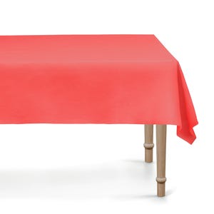 May include: A coral-coloured rectangular tablecloth draped over a wooden table. The table has four light-coloured wooden legs. The tablecloth is made of a smooth fabric and covers the entire table surface.