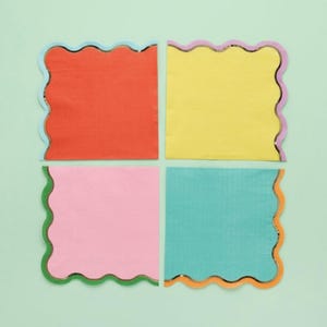 May include: Four square napkins with scalloped edges and metallic trim. The napkins are in the colors orange, yellow, pink, and teal.