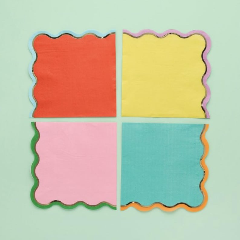 May include: Four square napkins with scalloped edges and metallic trim. The napkins are in the colors orange, yellow, pink, and teal.