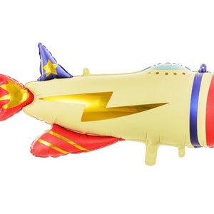 May include: A yellow and red airplane shaped foil balloon with a blue star on top and a gold lightning bolt design. The balloon has a blue and white propeller and a red and gold tail.