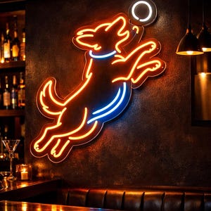 May include: Neon sign depicting a dog leaping for a disc. The sign features a bright orange outline with blue and white accents, mounted on a dark textured wall. The scene is set in a bar with a wooden bar top and dim lighting.