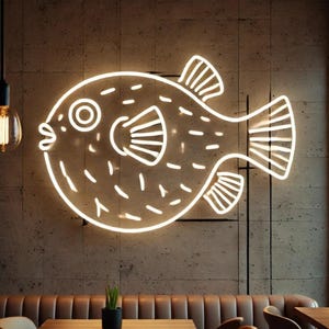 May include: White neon sign of a pufferfish on a brown brick wall. The sign is a simple outline of a pufferfish with a large eye and a fin on its back.