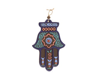 May include: A blue and green hand-shaped wall hanging with intricate floral designs and a central star. The hand is a traditional symbol of protection and good luck.