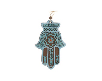 May include: A blue and brown hamsa hand wall hanging with intricate details and a small red jewel in the center.