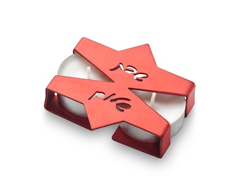 May include: Red metal candle holder shaped like a Star of David with the Hebrew words "ner tamid" (meaning "eternal light") inscribed on it. The holder is designed to hold two tea lights.