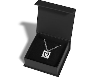 May include: A silver necklace with a square pendant featuring a cut-out heart design. The necklace is displayed in a black velvet-lined jewelry box.
