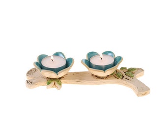 May include: A ceramic candle holder shaped like a branch with two teal blue flower-shaped candle cups. Each cup holds a white tea light candle.