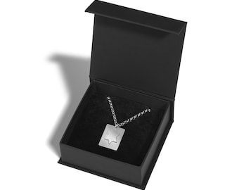 May include: A silver necklace with a square pendant featuring a cut-out star of David design. The necklace is displayed in a black velvet box.